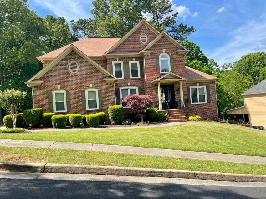 Brick home with new white windows and a landscaped lawn